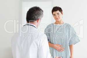 Brunette Woman in hospital gown talking to her doctor