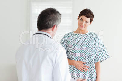 Young Woman in hospital gown talking to her doctor