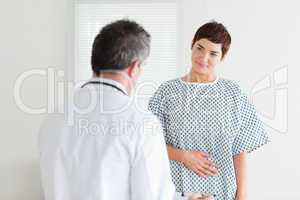 Young Woman in hospital gown talking to her doctor