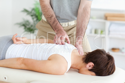 Masseur massaging a brunette woman's shoulder