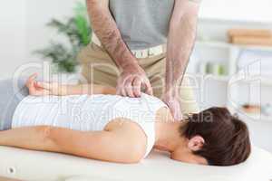 Masseur massaging a brunette woman's shoulder