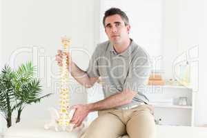 Chiropractor holding the model of a spine
