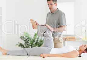 Chiropractor stretching a customer's leg