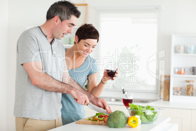 Man cutting vegetables while is woman is watching