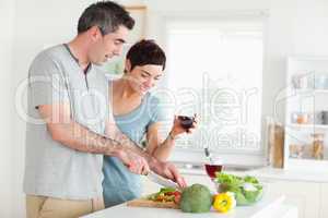 Man cutting vegetables while is woman is watching