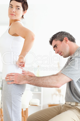 Chiropractor examining a brunette woman's back
