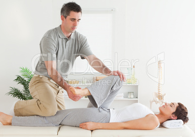 Chiropractor stretching young woman's leg