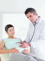 Doctor listening into the belly with a stethoscope