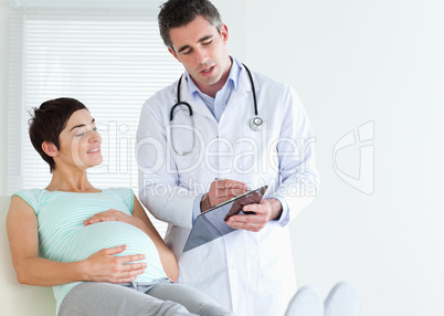 Pregnant woman lying down talking to her doctor