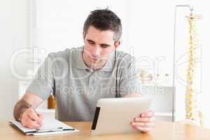 Man sitting at a table with a tablet and a chart