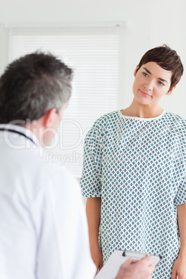 Cute Woman in hospital gown talking to her doctor