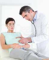 Doctor listening into the woman's belly with a stethoscope