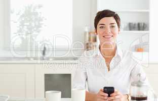 Woman with phone and coffee looking to camera
