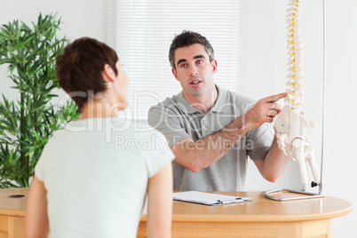 Male Doctor showing a patient a part of a spine