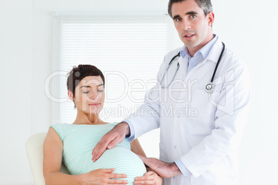 Male Doctor examining a pregnant woman's tummy
