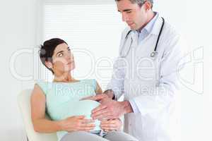 Doctor ausculating a pregnant woman's belly