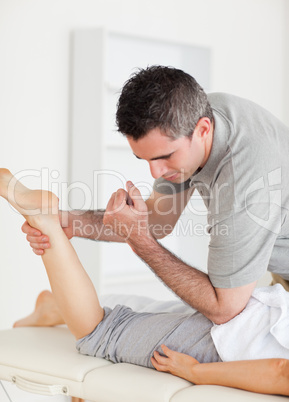 Chiropractor stretches female customer's leg