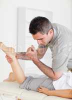 Chiropractor stretches female customer's leg