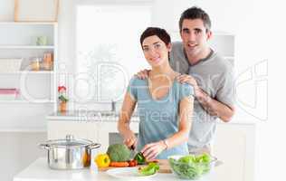 Husband massaging his wife while she is cutting vegetables