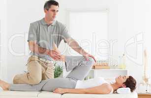 Chiropractor stretching customer's leg