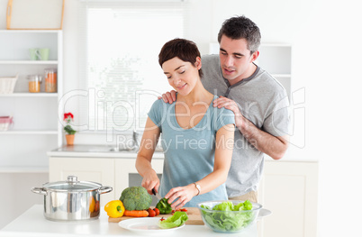 Man massaging his wife while she is cutting vegetables