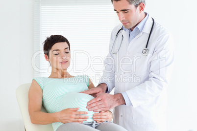 Doctor ausculating a pregnant woman's tummy