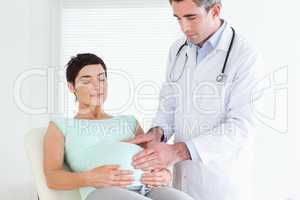 Doctor ausculating a pregnant woman's tummy