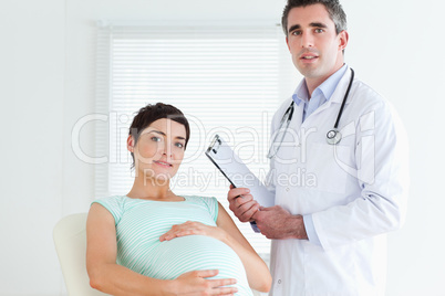 Male Doctor and pregnant patient looking at the camera