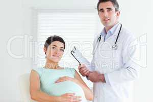 Male Doctor and pregnant patient looking at the camera