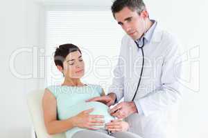 Male Doctor listening into the belly with a stethoscope