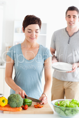 Woman cutting vegetables and man holding plates