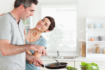 Woman smiling at her pan-holding husband
