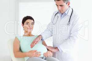 Male Doctor ausculating a pregnant woman's tummy