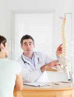 Male Doctor showing a female patient a part of a spine