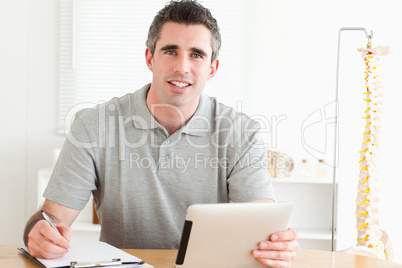 Male Doctor sitting working with a tablet and a chart