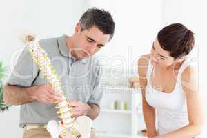 Chiropractor and patient looking at a model of a spine