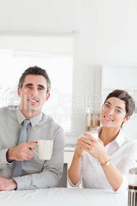 Smiling couple drinking coffee looking into the camera