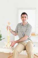 Chiropractor holding a model-spine looking into the camera