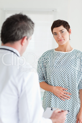 Charming Woman in hospital gown talking to her doctor
