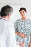 Charming Woman in hospital gown talking to her doctor