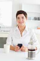 Cute woman with mobile phone in the kitchen