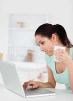 Young woman with cup of coffee at by her laptop