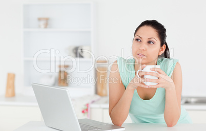 Thoughtful young woman with laptop and coffee