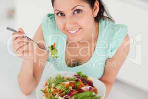 Cute young woman eating salad