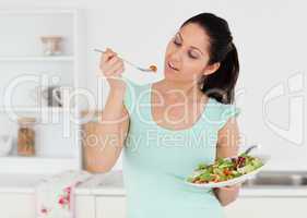 Casual young woman eating salad