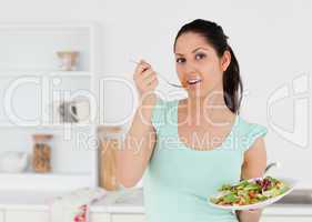 Lovely young woman with salad in kitchen