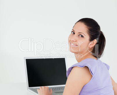 Smiling young woman sitting by laptop