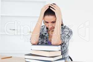 Depressed young student leaning on books