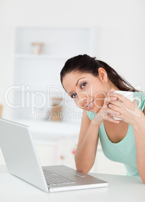 Young woman with cup of coffee by her pc