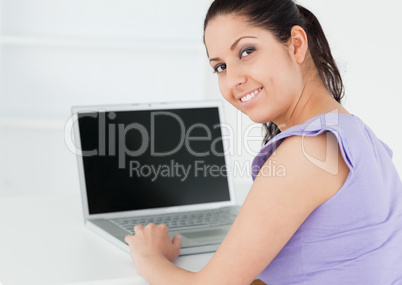 Cute young woman sitting by laptop